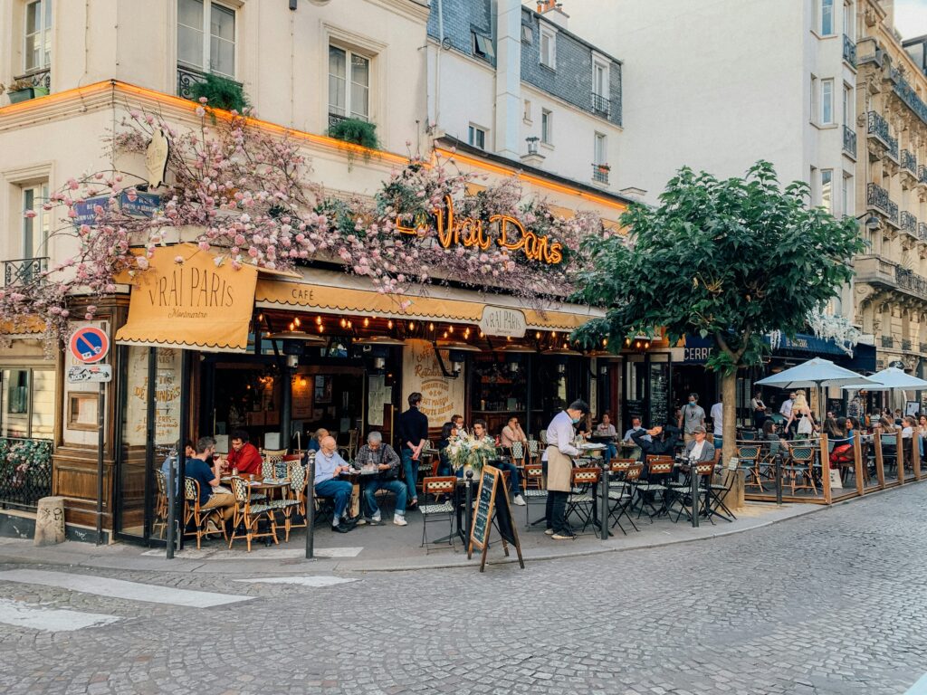 A parisian restaurant with a faux floral display outsite.