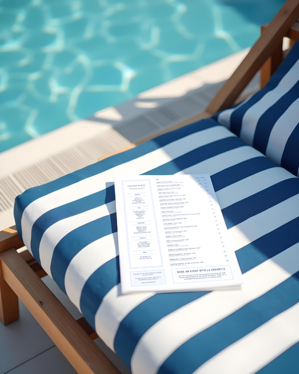 A brasserie menu sitting on top of a striped poolside lounger