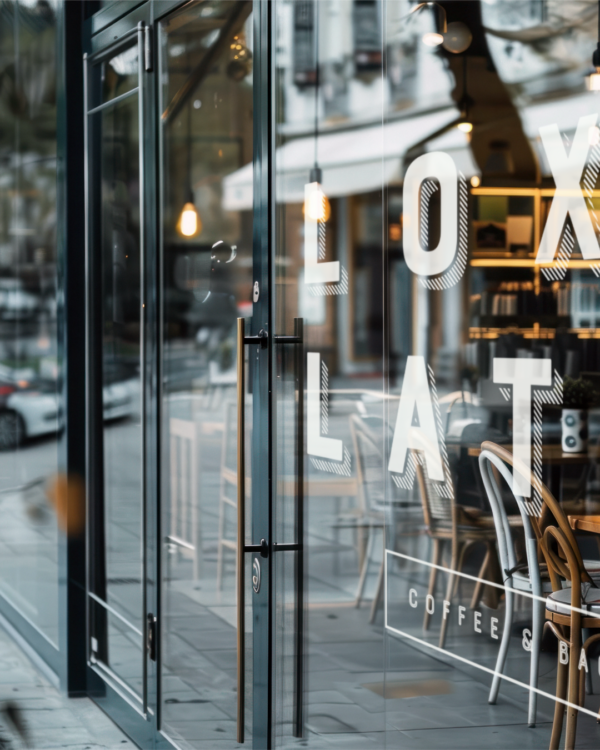 A closeup of a restaurant window with the "Lox & Latte" logo decal on the front in white.