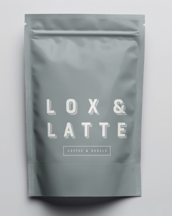 A packaged coffee bag in sage green with the "Lox and Latte" logo in white lettering, sitting on top of a flat grey surface.