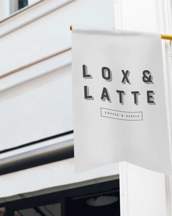 A cloes up of a white flag outside of a white building featuring the black "lox and Latte" logo on the front.